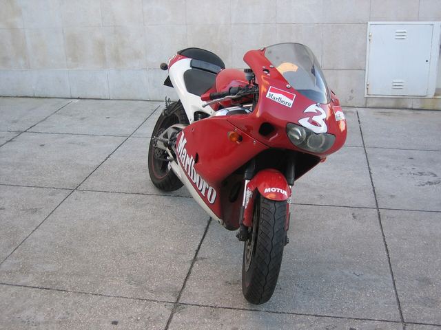 Rood-witte Aprilia RS 125 geparkeerd op een tegelvloer