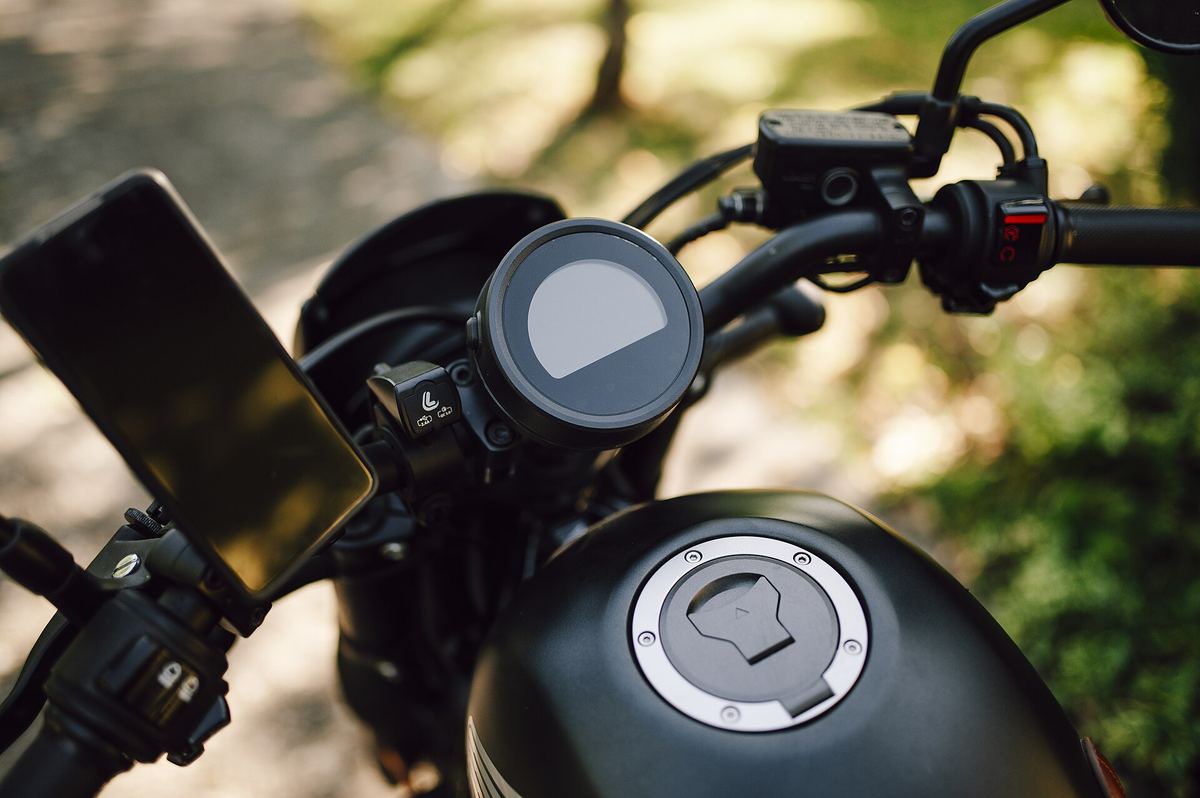 Stuur van een motor met een rond dashboard en een gsm in een houder